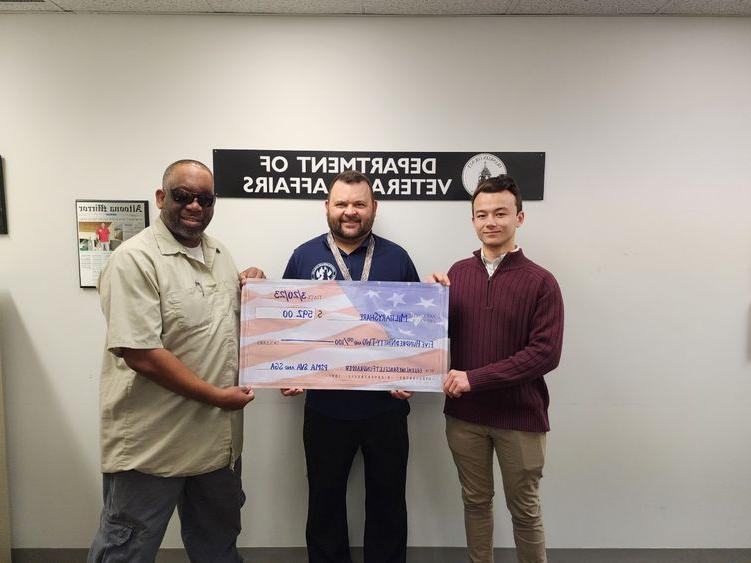 Students hold a check written out to MilitaryShare Program